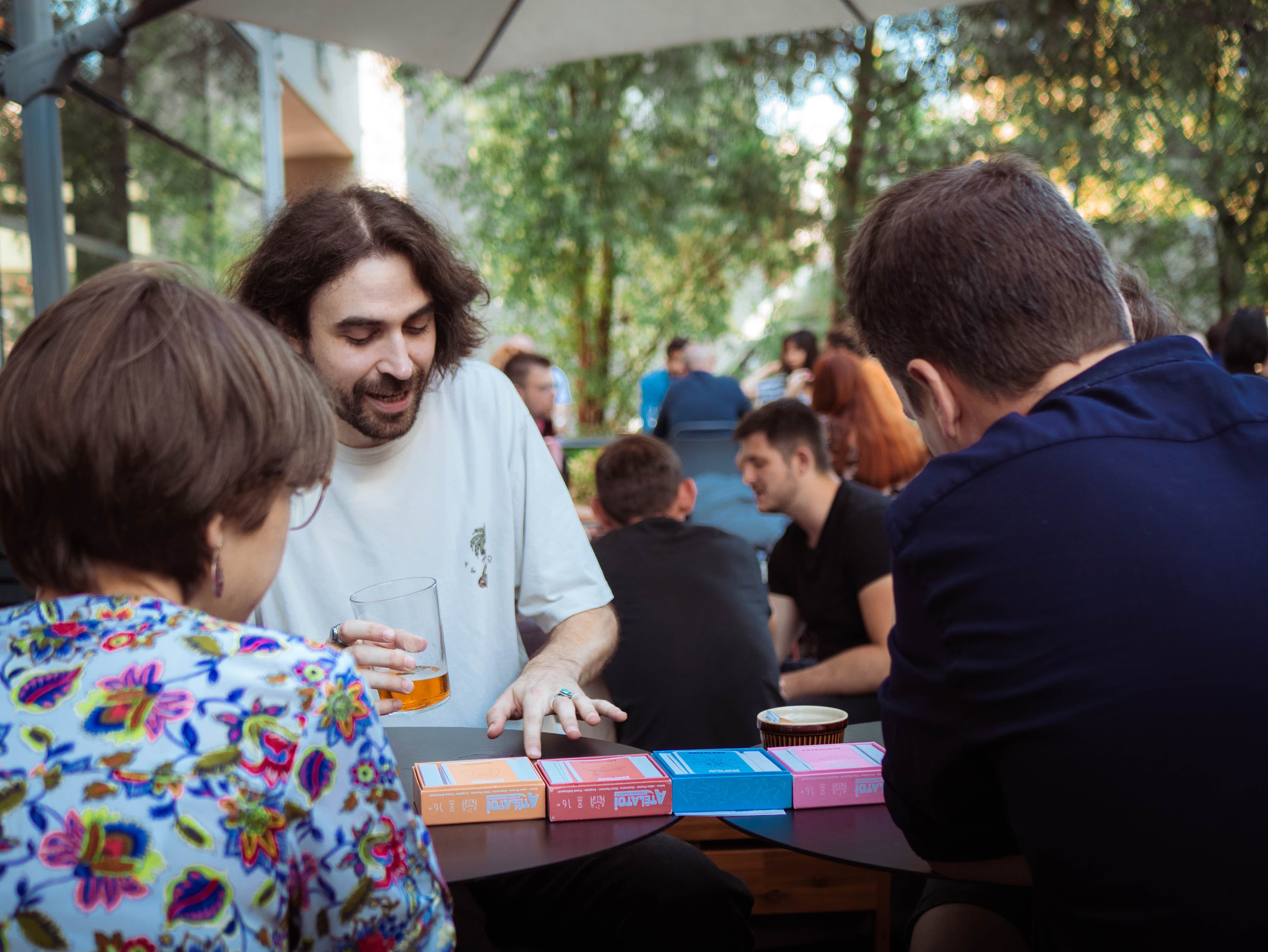 Un groupe d'amis autour d'une table, jouant avec les cartes Atélatoi