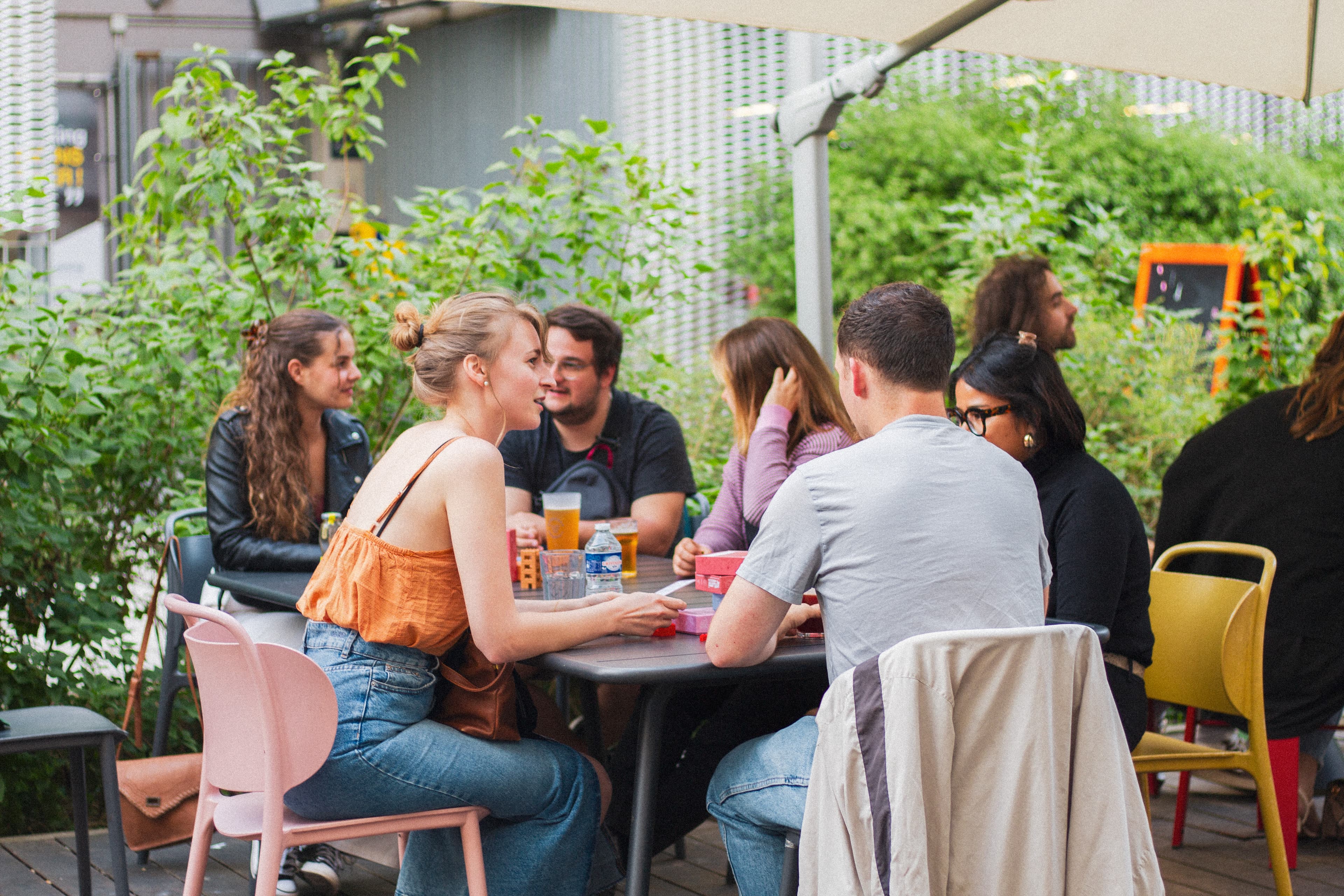 Un groupe d'amis souriants autour d'une table lors d'une soirée Atélatoi